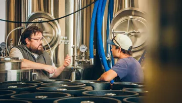 Two men discussing in a brewery setting.