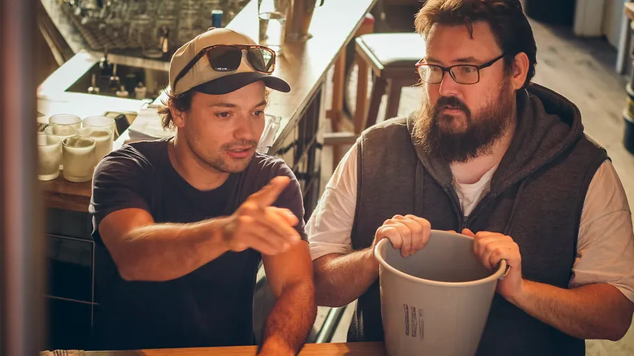 Two men talking at a bar counter.