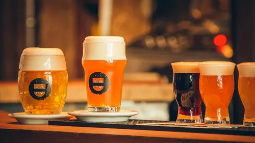 Five beers with foam on a wooden bar.