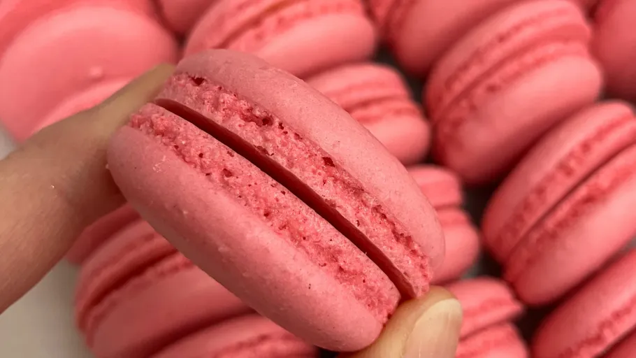 Rosa Macarons in Hand zwischen anderen.