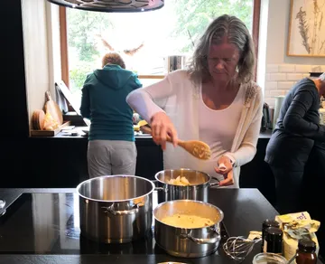 Frau kocht in einer Küche, rührt Töpfe.