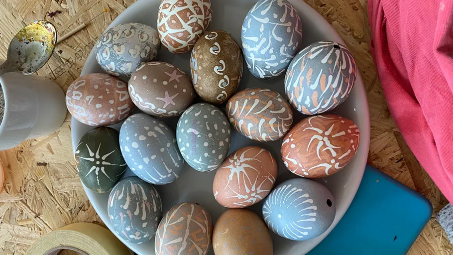 Decorated eggs on a white plate, wooden background.