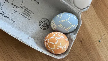 Dekorierte Eier in einem Karton auf Tisch.