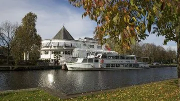 Boat docked by a riverside building.