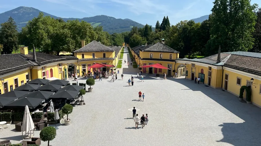 People walking in courtyard with yellow buildings.