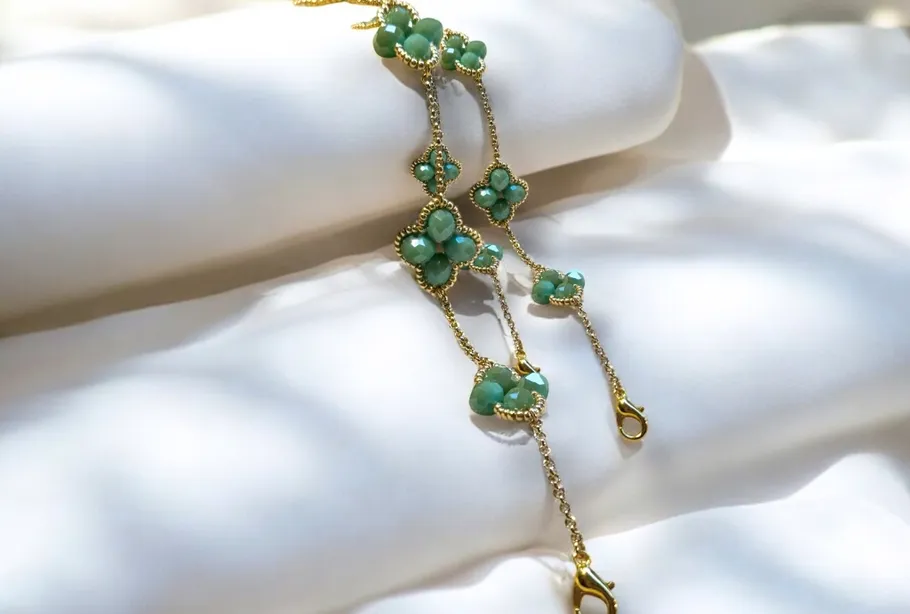 Gold chain with green stones on white background.