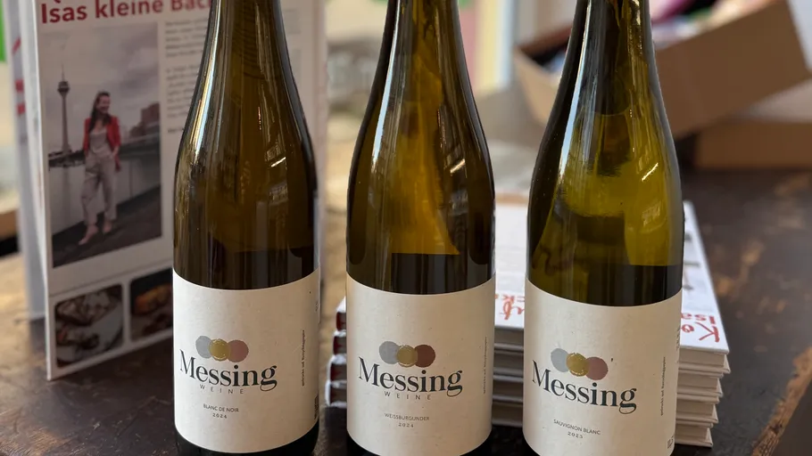 Three wine bottles on a wooden table.