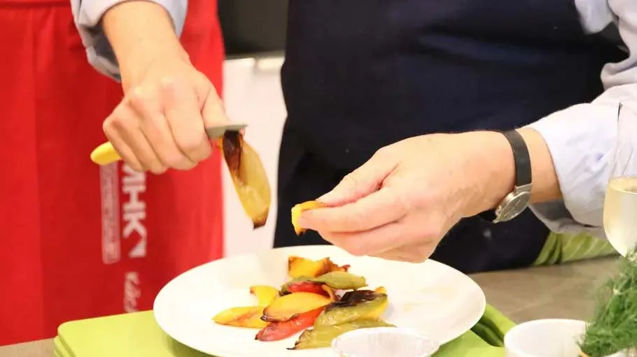 Person peeling roasted bell peppers on plate.