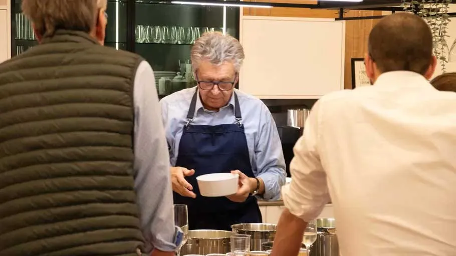 Man in apron holding bowl in kitchen.