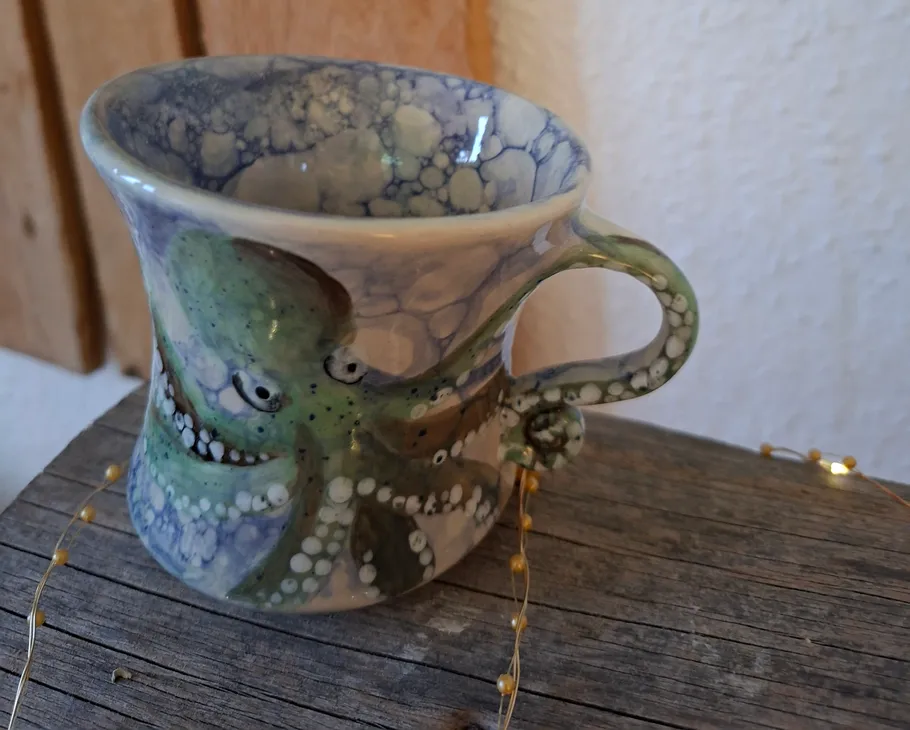 Keramikbecher mit Oktopus-Design auf Tisch.