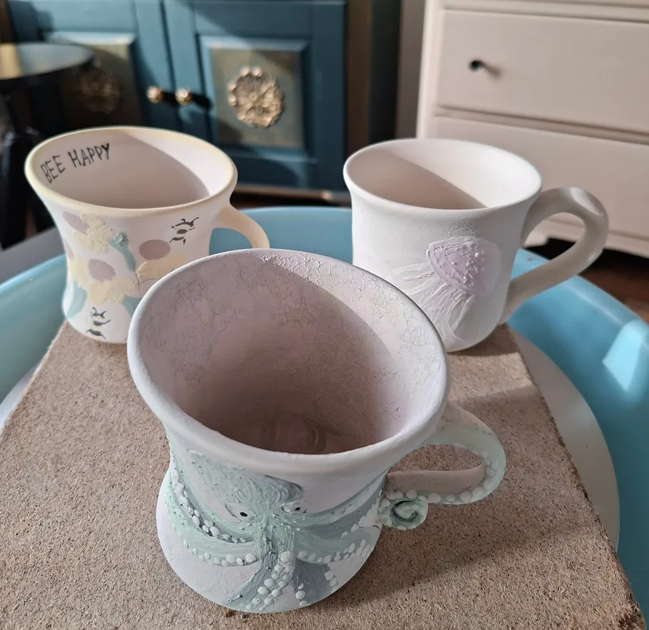 Three decorated ceramic mugs on a tray.