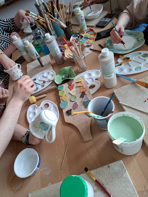 Personen bemalen Keramik bei einem Tisch-Workshop.