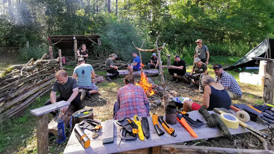 Group sitting around campfire in wooded area.