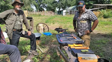 Zwei Männer begutachten Messer auf Tisch im Freien.