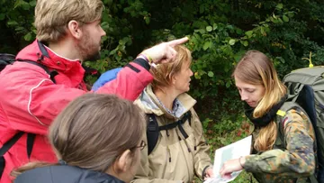 Gruppe von Wanderern diskutiert mit Karte im Wald.