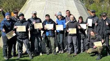 Gruppe hält Zertifikate, steht draußen und lächelt.