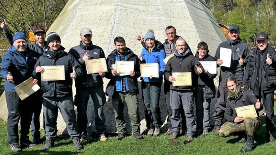 Group holding certificates, standing outdoors smiling.