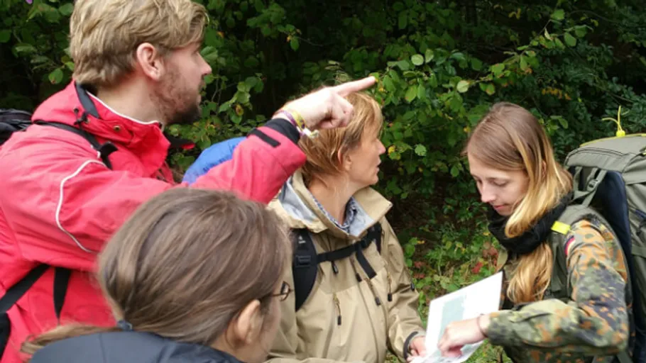 Group of hikers with a map in forest.