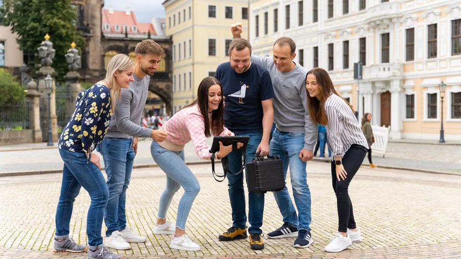 Gruppe schaut begeistert auf Tablet auf Straße.