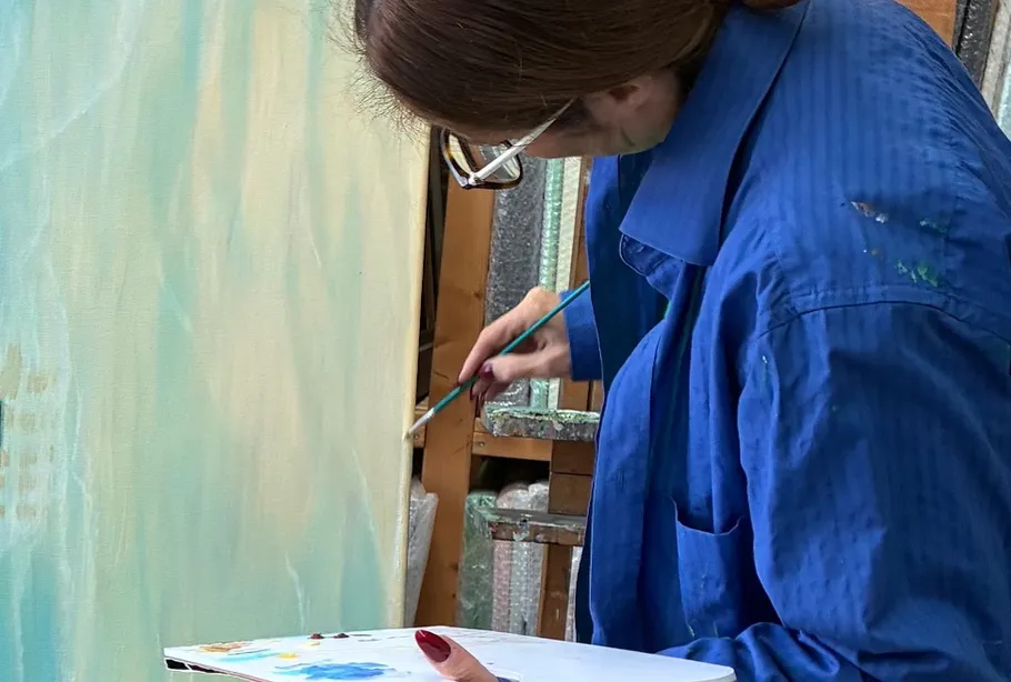 Person painting on canvas in studio.