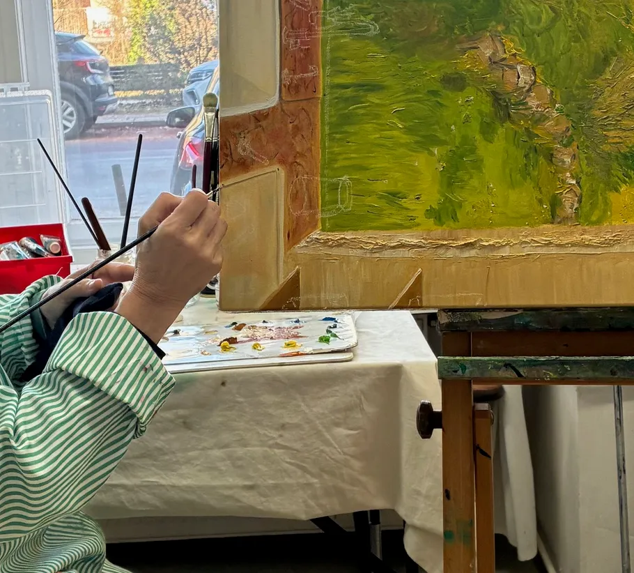 Artist painting on canvas in a studio.