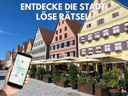 Hand holding phone, historic buildings, sunny day.