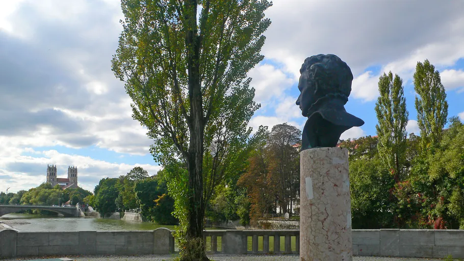 Bust on pedestal, trees and river nearby.