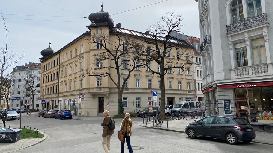 People walking near historic building on city street.