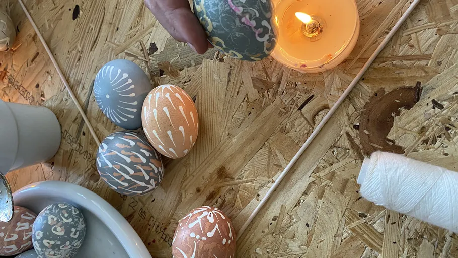 Decorated eggs beside candle on table.