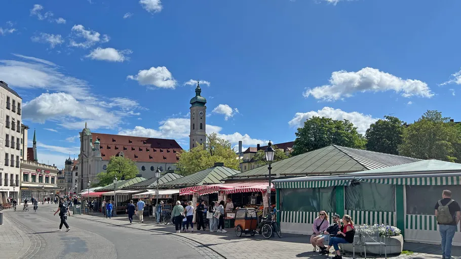 People browse stalls at outdoor market square.