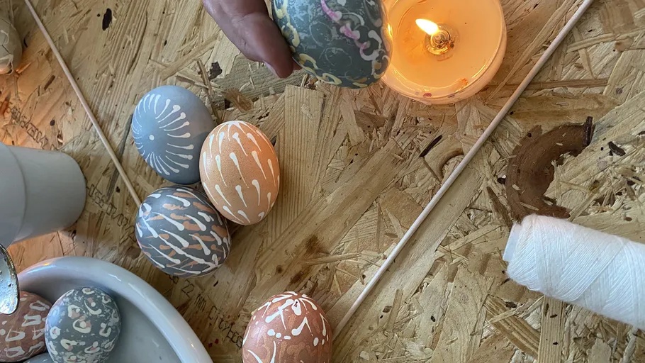 Decorated eggs next to lit candle on table.