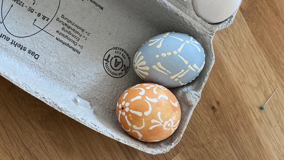 Dekorierte Eier in einem Karton auf einem Tisch.