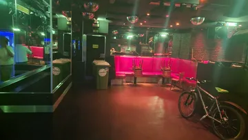 Leerer Nachtclub mit rosa Sitzecken und Fahrrad.
