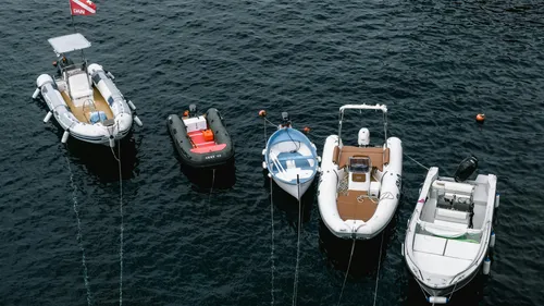 Fünf Boote auf ruhigem Wasser vertäut.