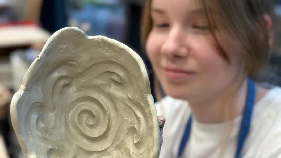 Person holding sculpted clay swirl design.