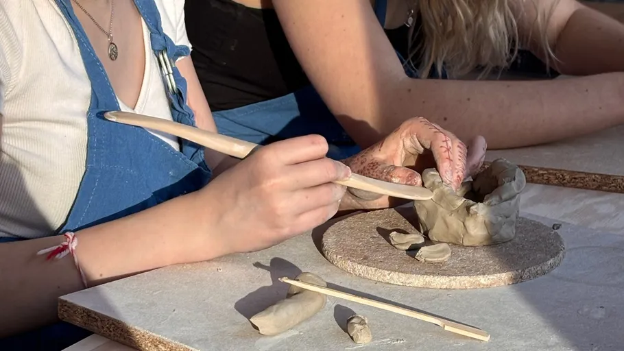 People shaping clay on a flat surface.