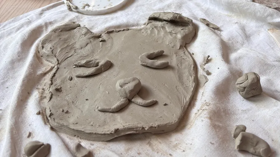 Clay bear face sculpted on cloth surface.