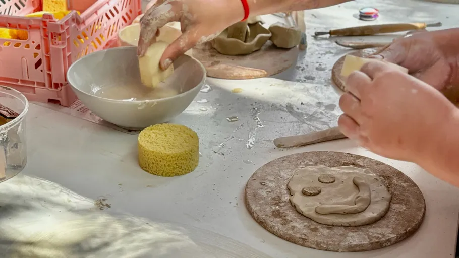 Hände töpfern auf einem unordentlichen Tisch.