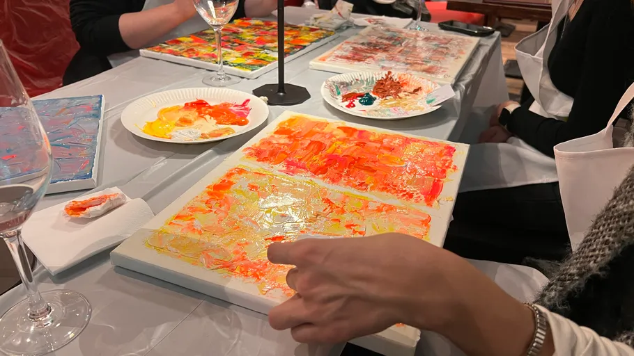 People painting colorful abstracts at a table.