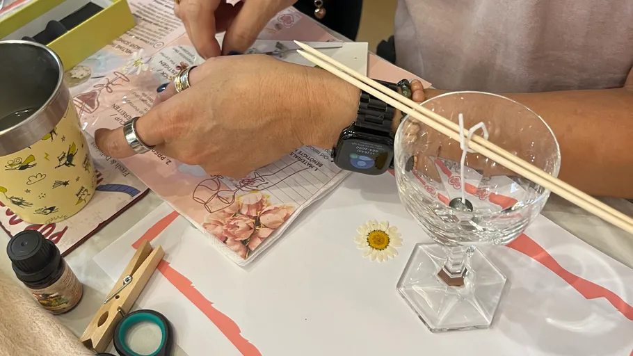 Person creating a candle on a table.