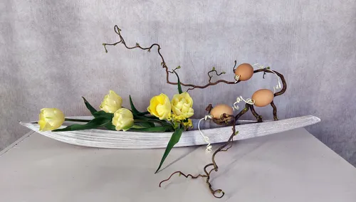Floral arrangement with yellow flowers and eggs.