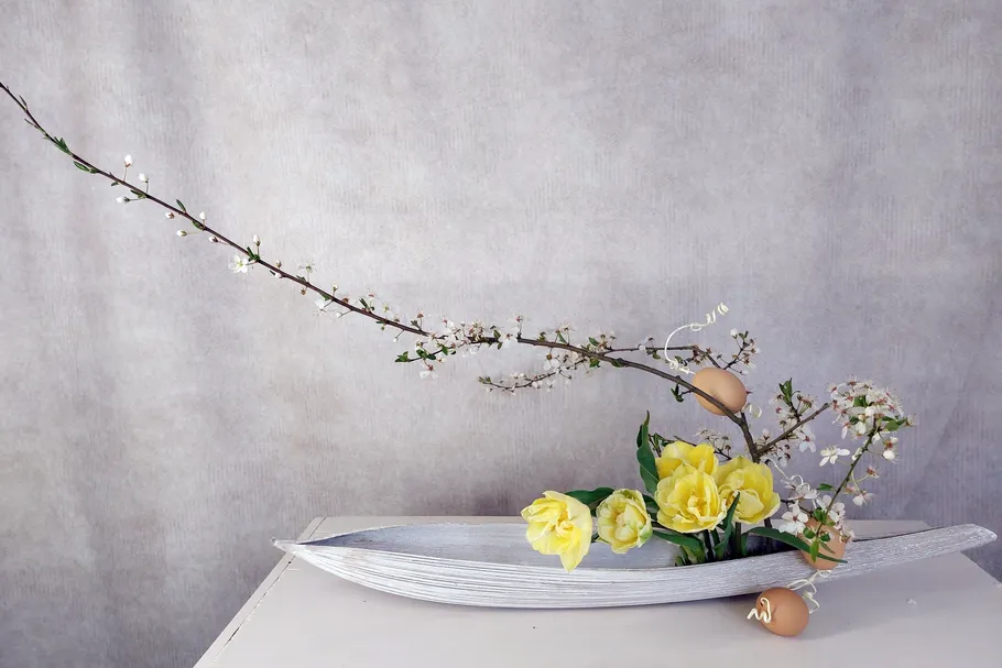 Floral arrangement with yellow flowers and branches.