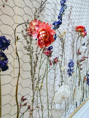 Bunte getrocknete Blumen an Drahtgeflechtwand.
