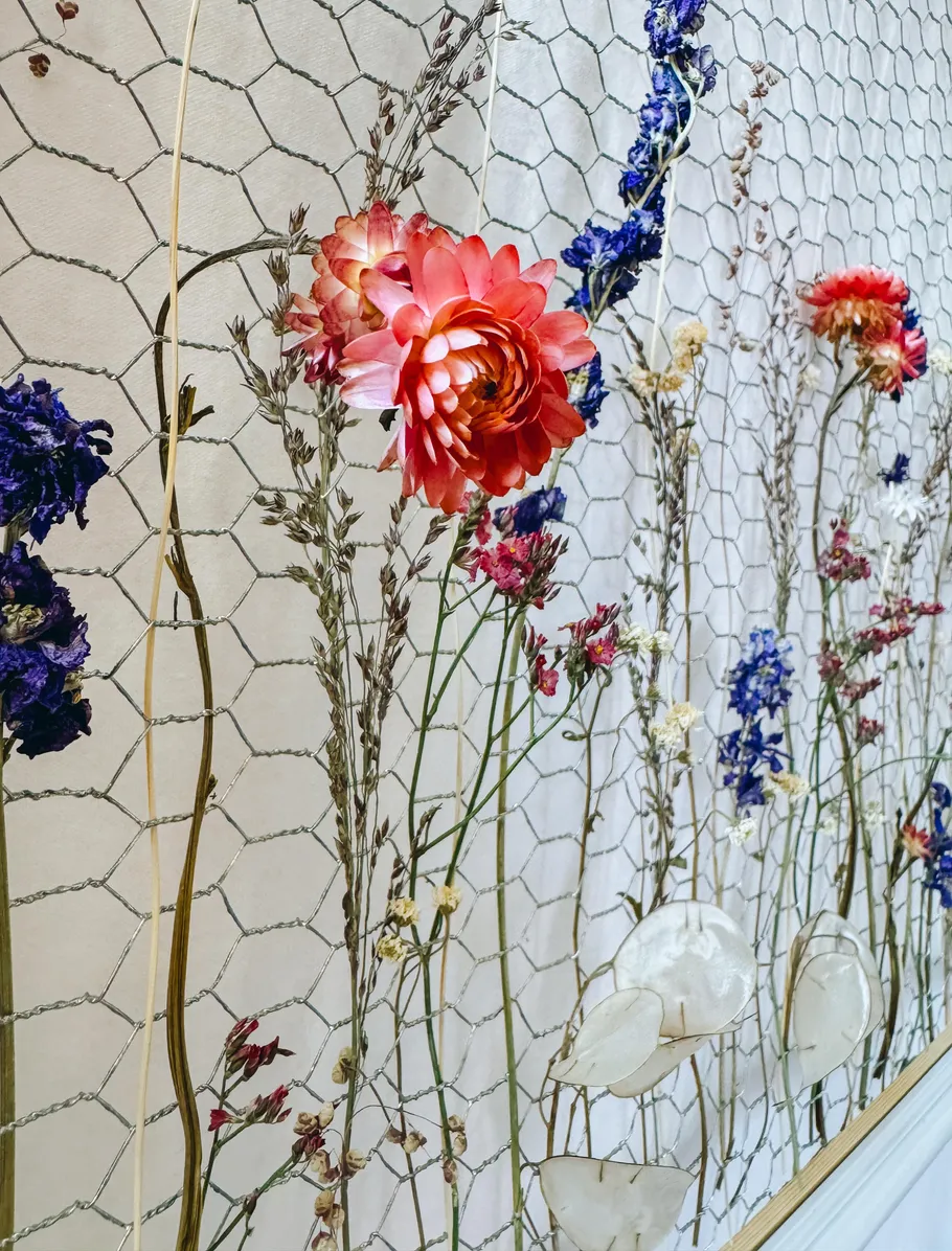 Colorful dried flowers on wire mesh wall.