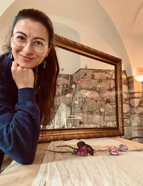 Smiling woman posing with framed flowers indoors.