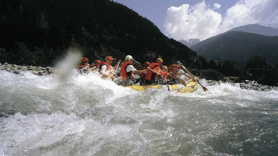 Rafting group paddling through river rapids.