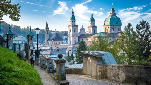 People walking on path near historic European buildings.
