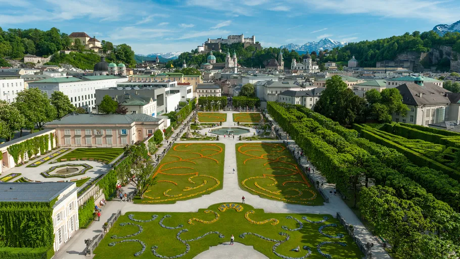 Colorful garden with city and fortress in background.