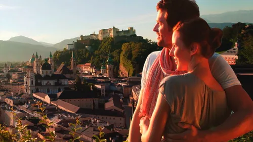 Couple embracing with Salzburg cityscape background.