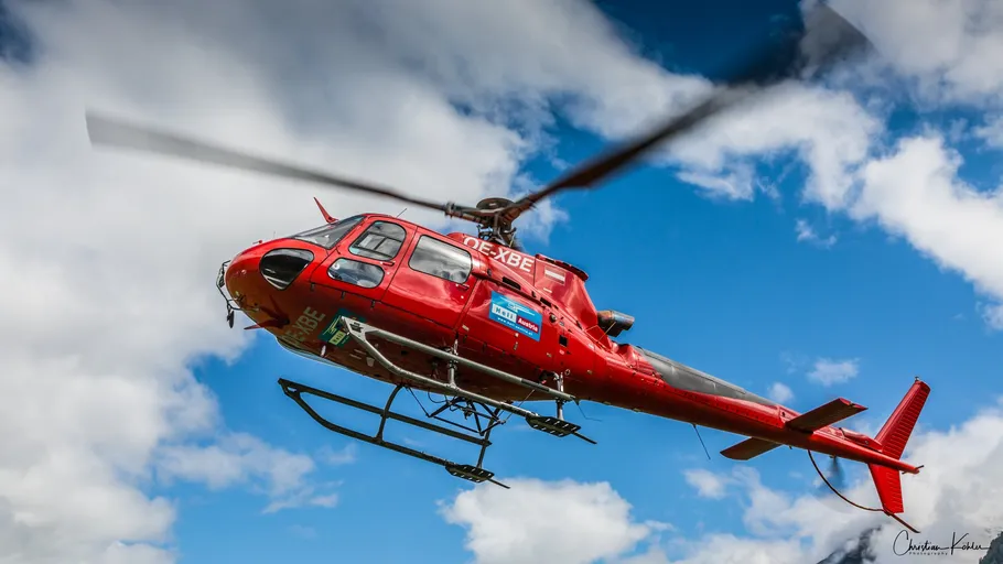 Roter Hubschrauber fliegt im wolkigen Himmel.